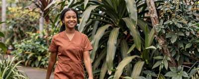 Female ER nurse walking through a lush botanical garden