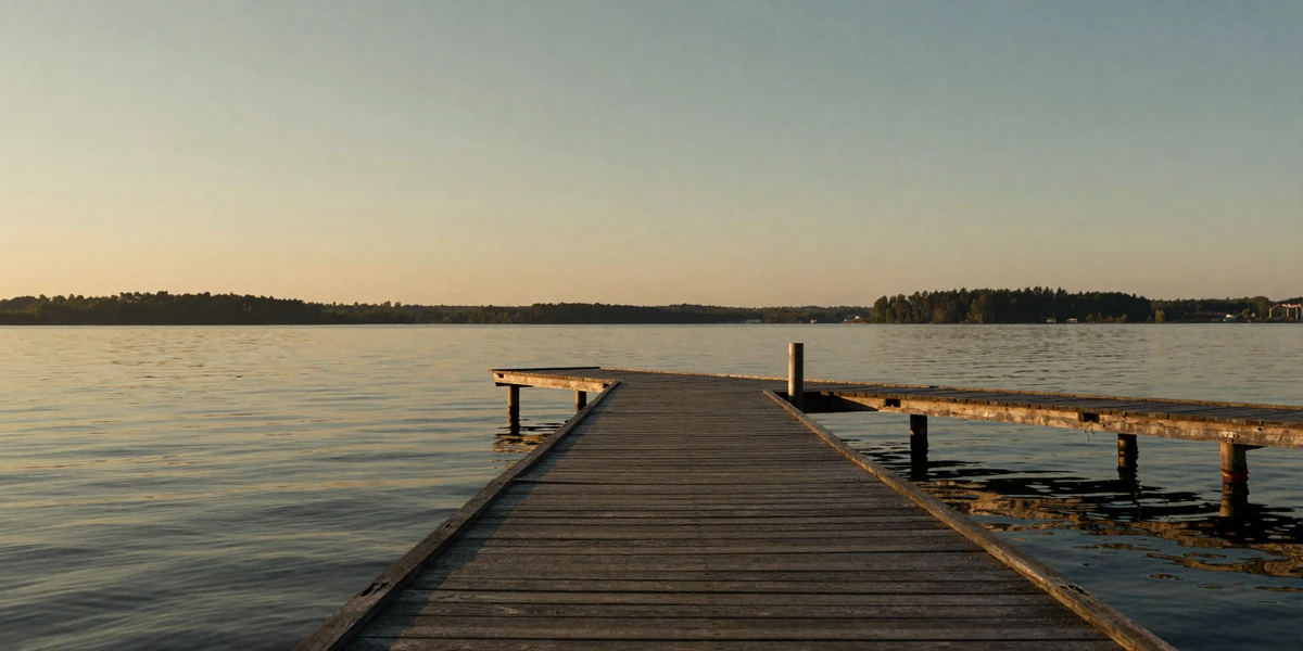 Tranquil lakeside dock at sunset with warm golden reflections