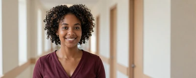 Black female medical assistant smiling in a bright clinic hallway