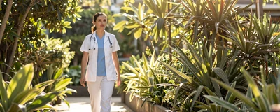 Female nurse midwife walking through a sunlit botanical garden