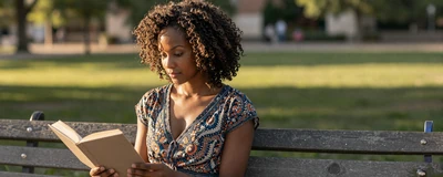 Female LPN reading a book in a sunlit park on her day off