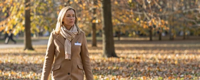 Female critical care nurse walking through a sunlit autumn park