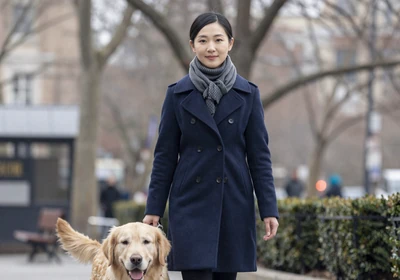 Woman doctor walking a golden retriever in a city park